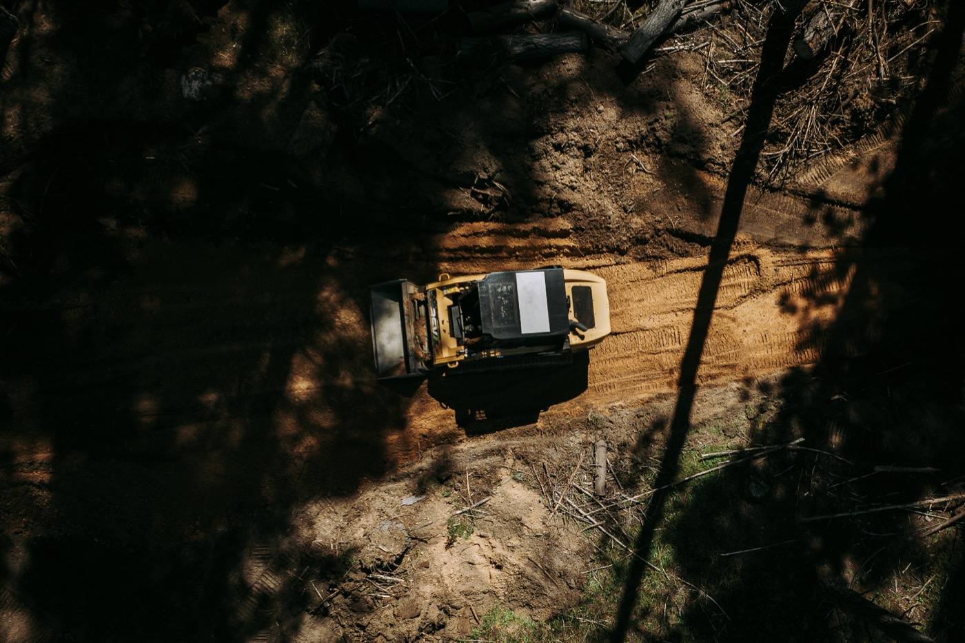 Top-down view of a compact loader shaping a freshly cut trail
