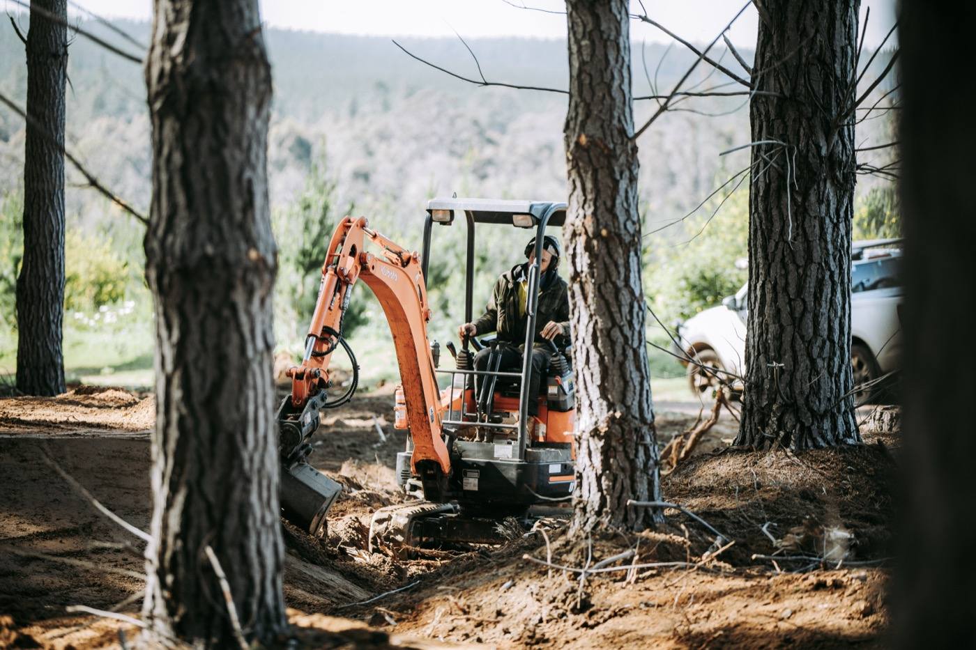 Dave at the controls of the excavator on site, mountain backdrop