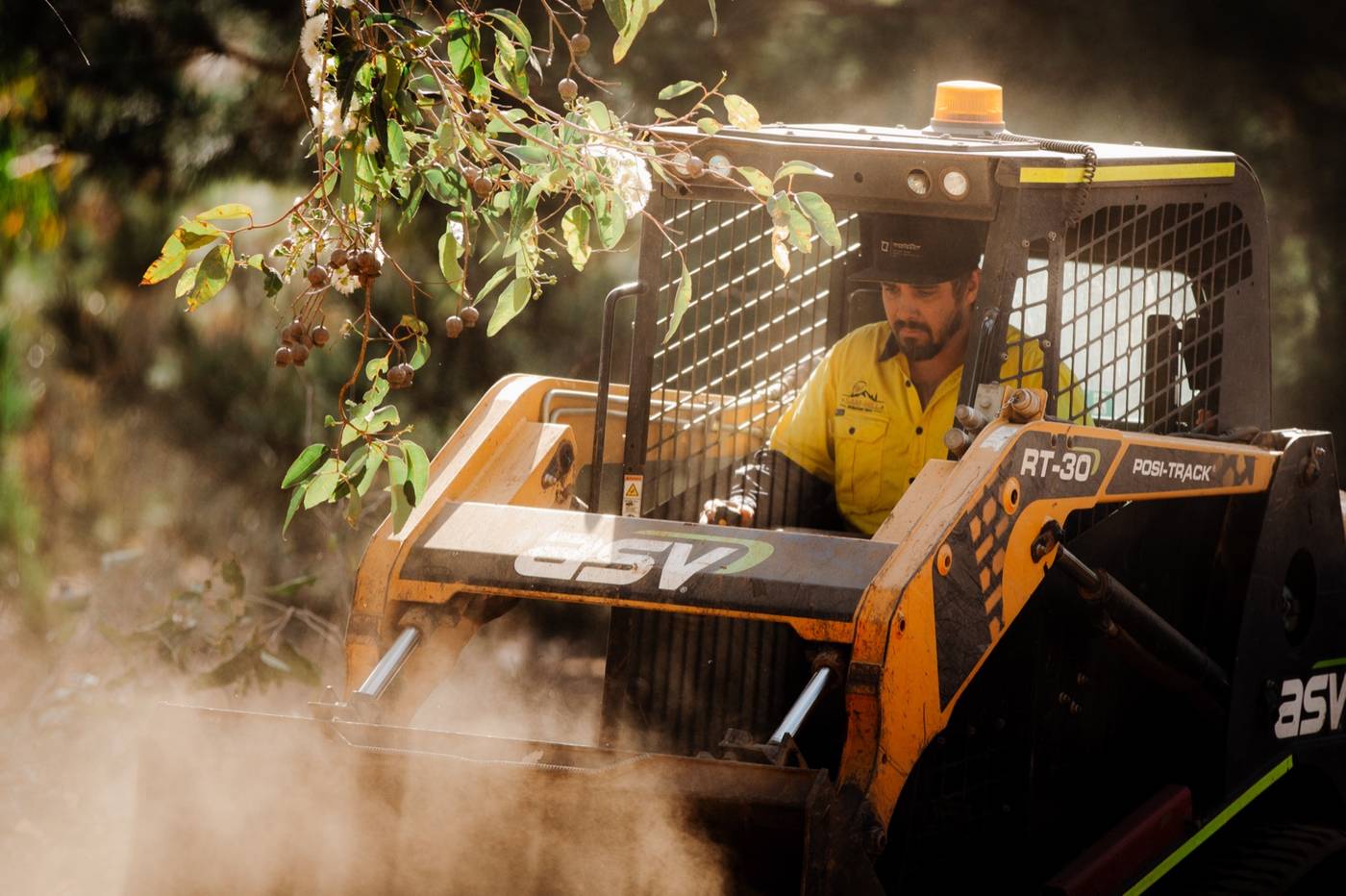 Operator in an ASV PosiTrack loader at Nannup, dust kicking up through the bush